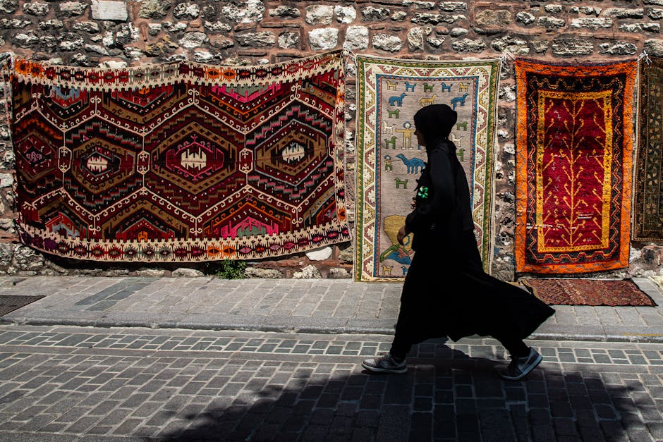 A silhouette of a woman walking past vibrant oriental rugs in Istanbul.